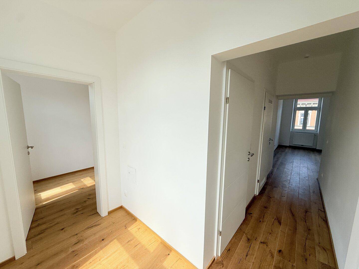 Geräumiger Flur mit Holzboden und mehreren Türen, verbindet verschiedene Wohnbereiche.