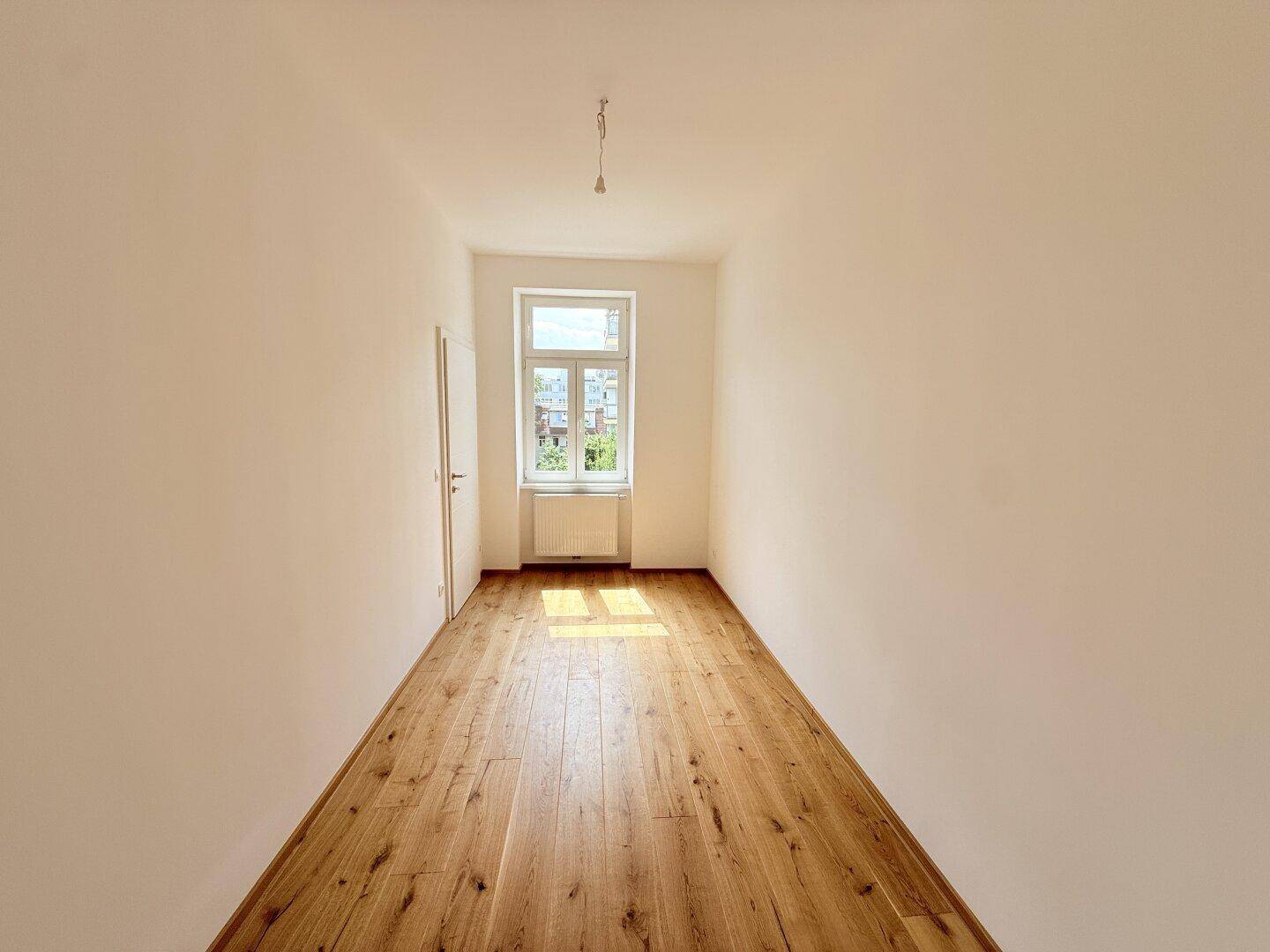 Heller Raum mit Holzboden und Fenster, bietet viel Tageslicht und eine angenehme Atmosphäre.
