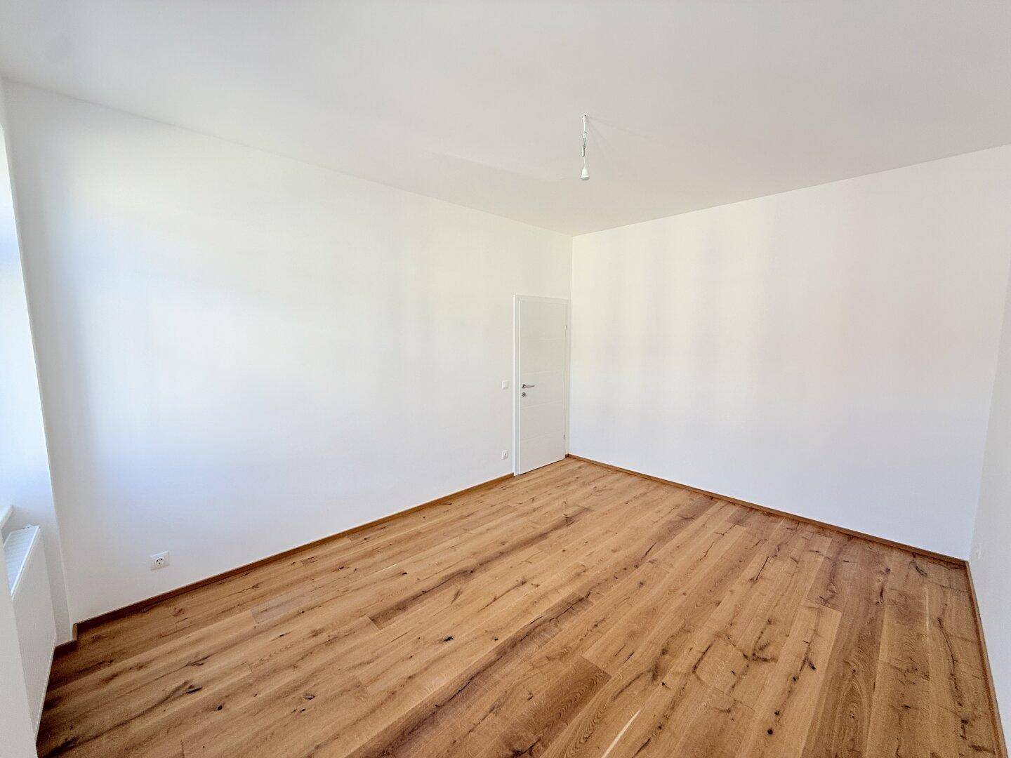 Heller Raum mit Holzboden und weiß gestrichenen Wänden, bietet vielseitige Nutzungsmöglichkeiten.