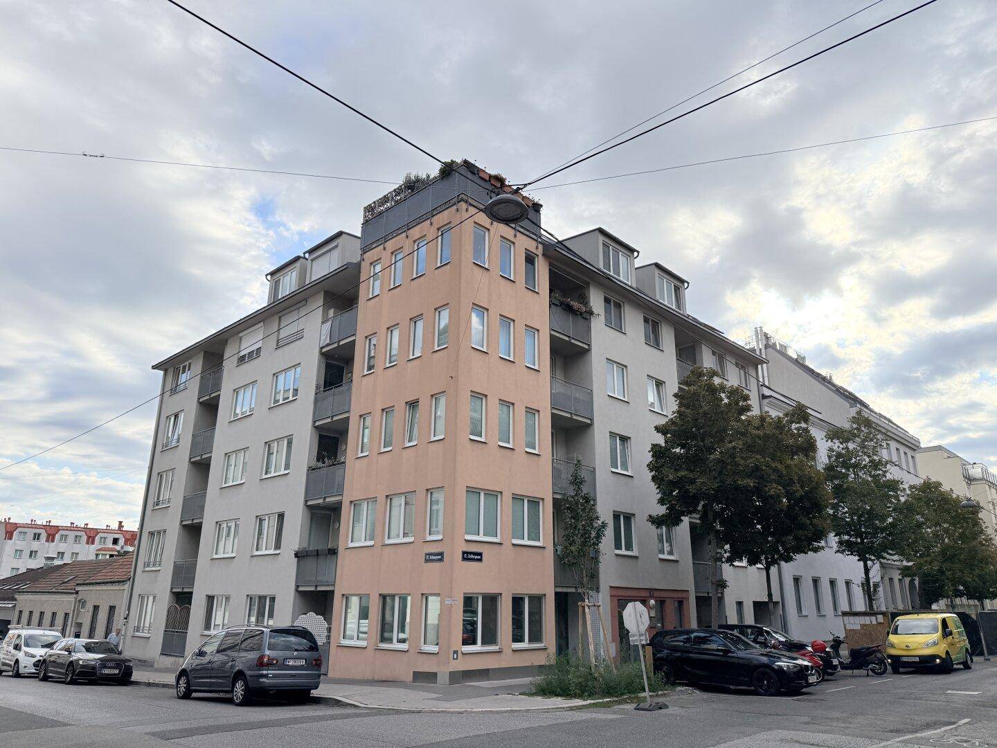 Eckgebäude mit moderner Architektur, Balkonen und urbaner Umgebung.