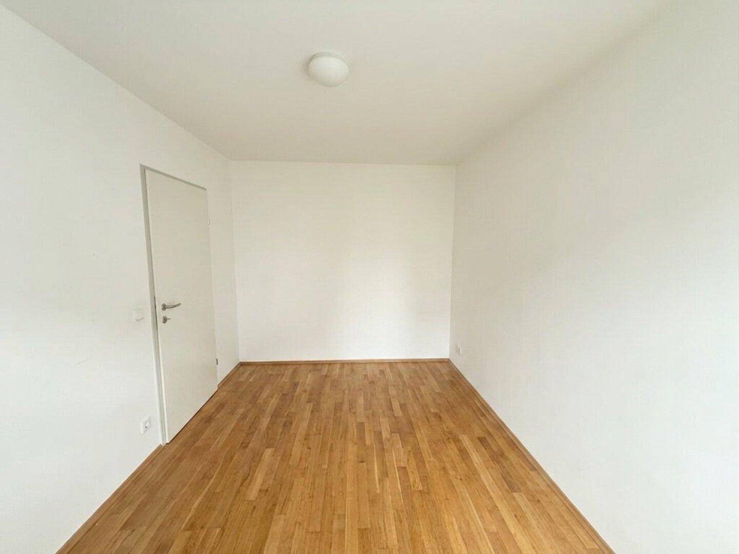 Leeres Schlafzimmer mit Holzboden und weißen Wänden, bereit zur Einrichtung.