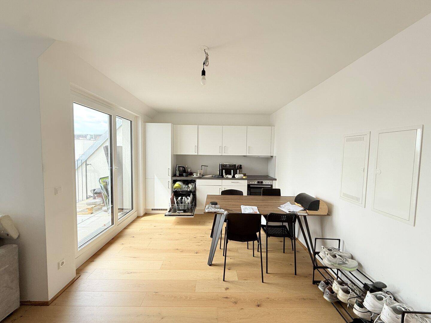 Offene Küche mit weißen Schränken, Esstisch und direktem Zugang zur Terrasse.