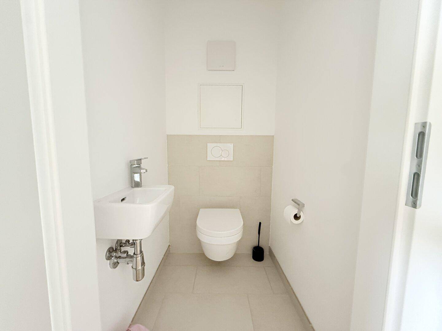 Modernes Gäste-WC mit wandhängender Toilette und kleinem Waschbecken.