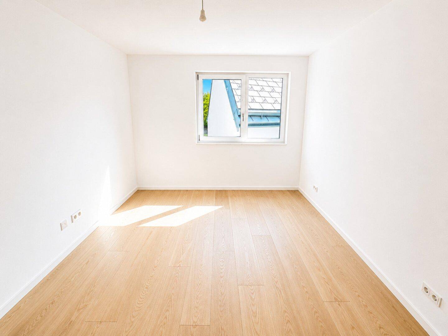 Helles Zimmer mit Holzboden und Fenster, das eine angenehme Wohnatmosphäre schafft.