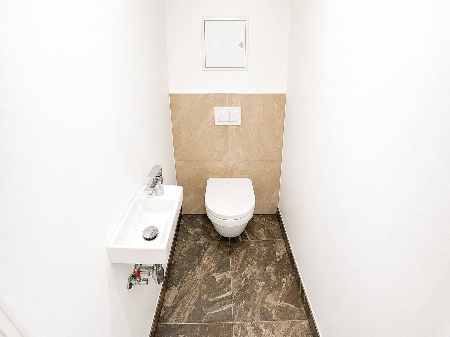 Funktionales Gäste-WC mit dunklem Fliesenboden und modernem Wand-WC in minimalistischem Design.
