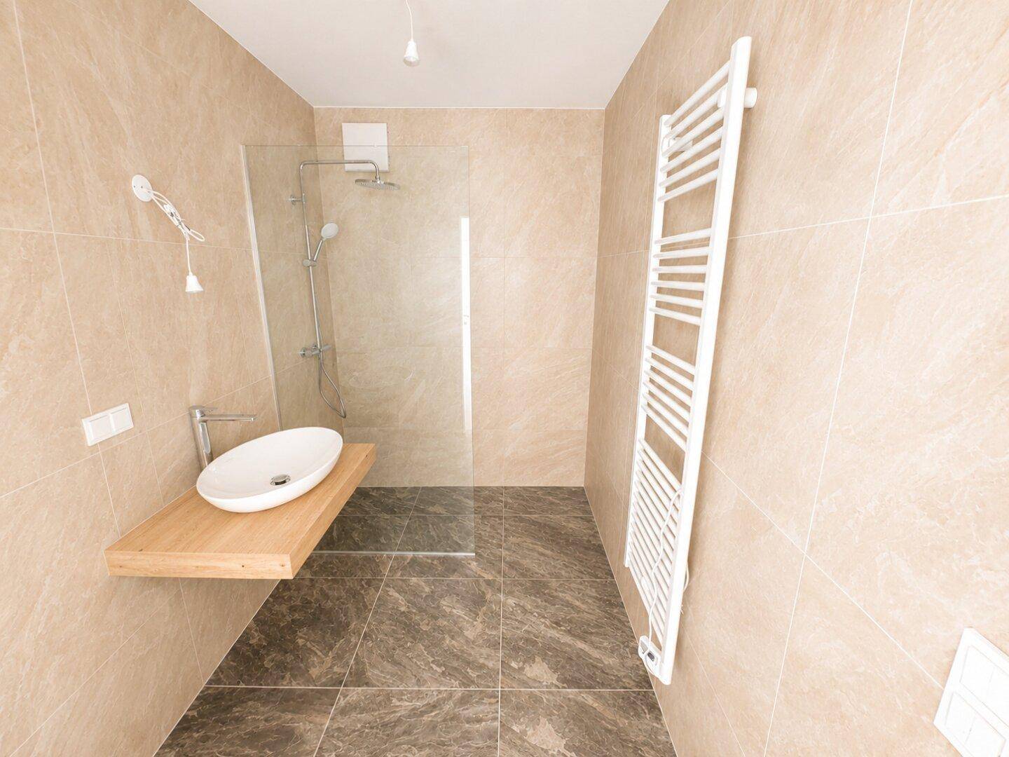 Modernes Badezimmer mit beigen und grauen Fliesen, begehbarer Dusche und Handtuchheizkörper.