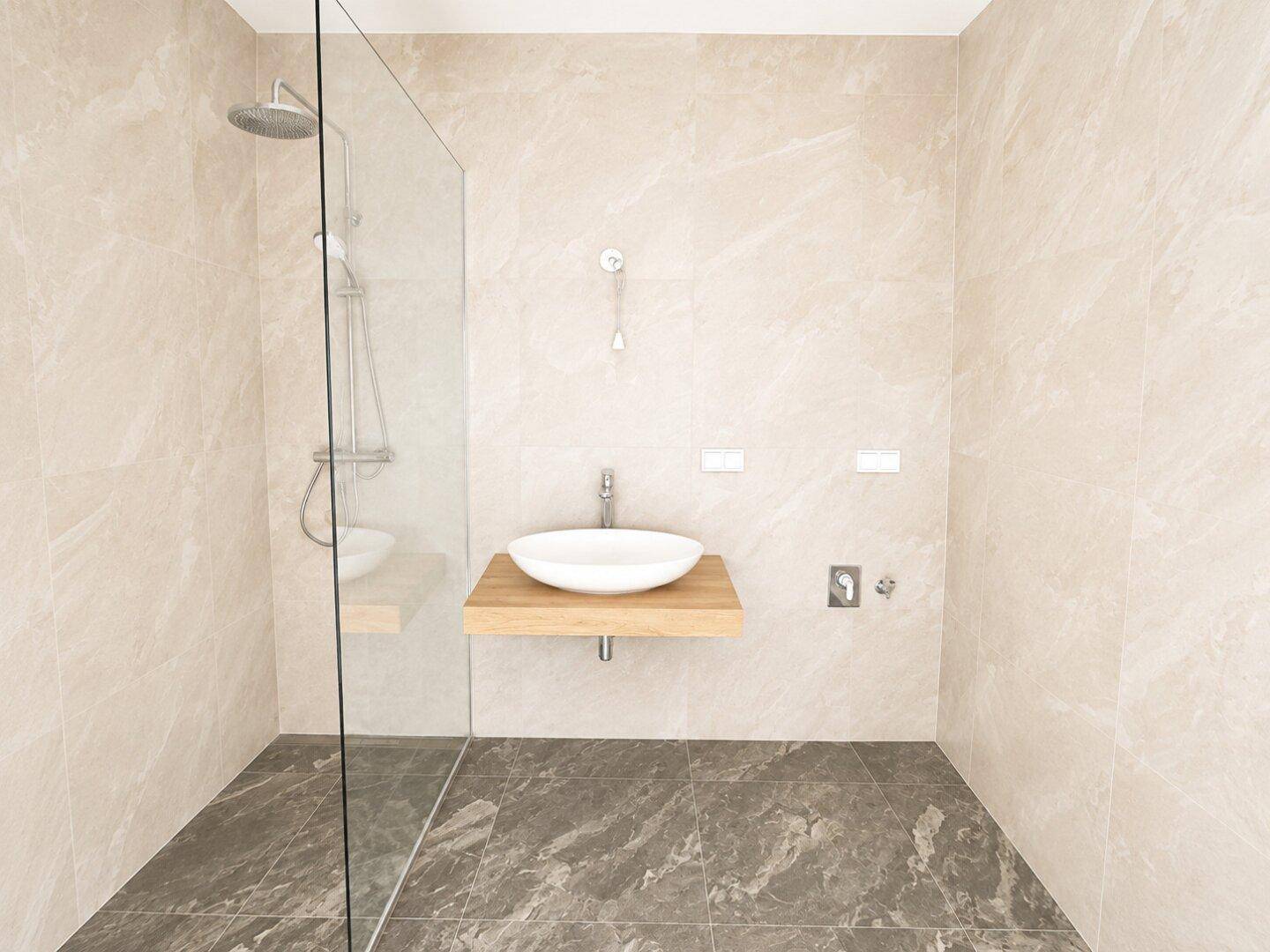 Modernes Badezimmer mit beigefarbenen Fliesen, ebenerdiger Dusche und schwebendem Waschbecken.