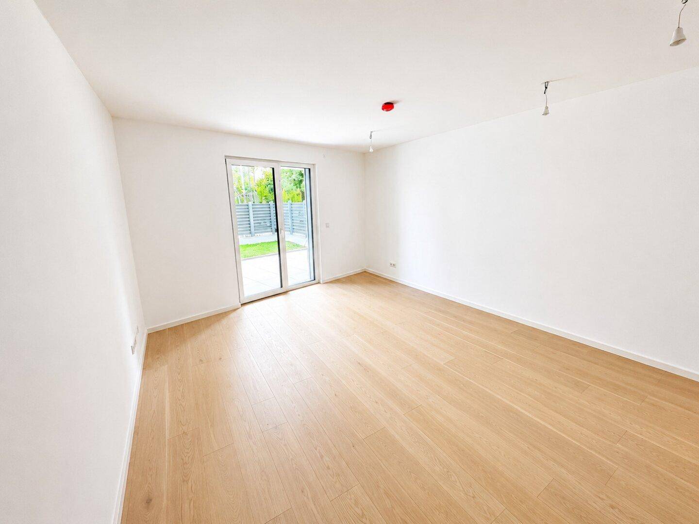 Lichtdurchfluteter Raum mit Schiebetür zum Außenbereich und hellem Holzfußboden.