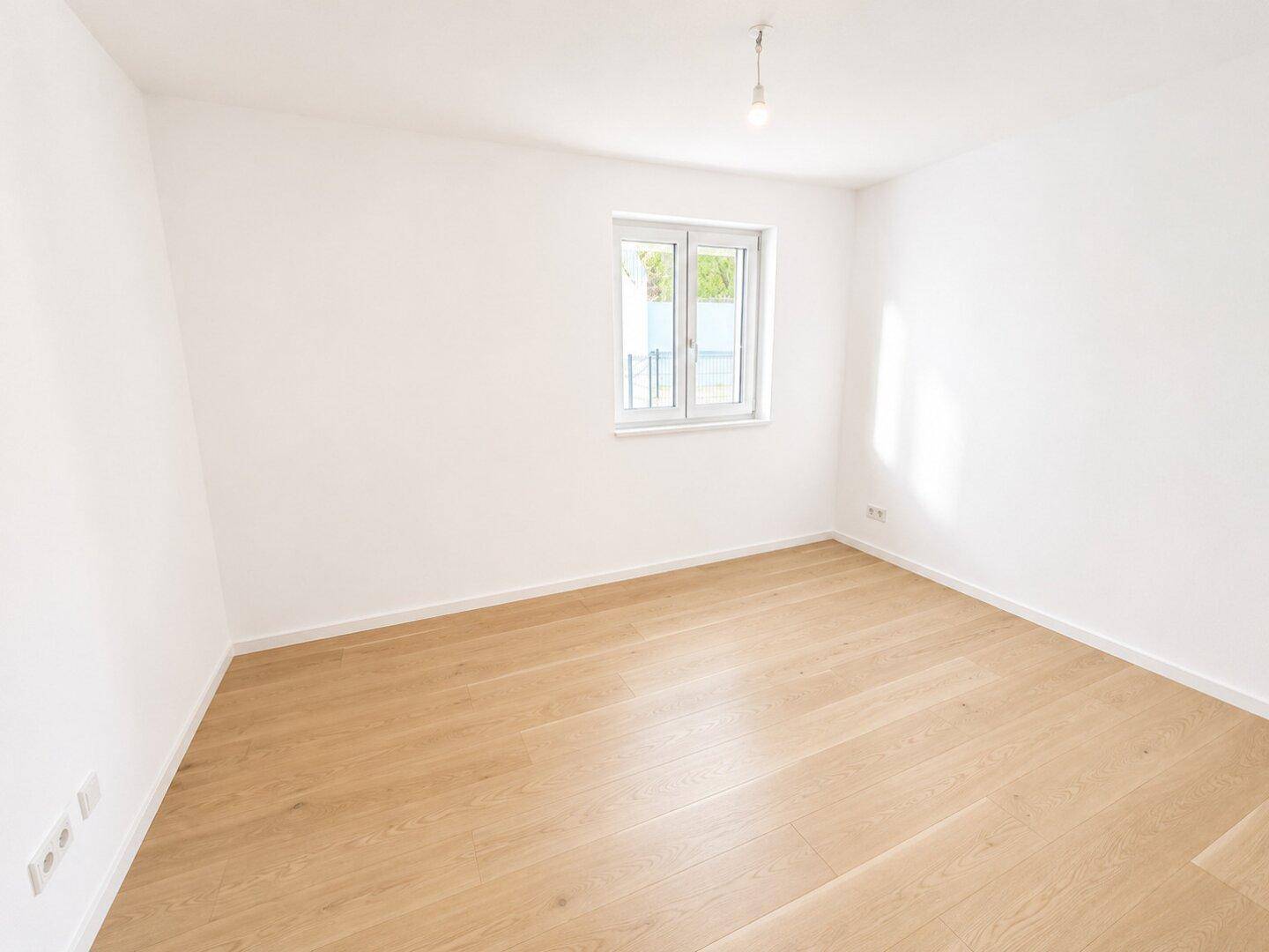Helles Schlafzimmer mit weiß gestrichenen Wänden und modernem Holzparkettboden.
