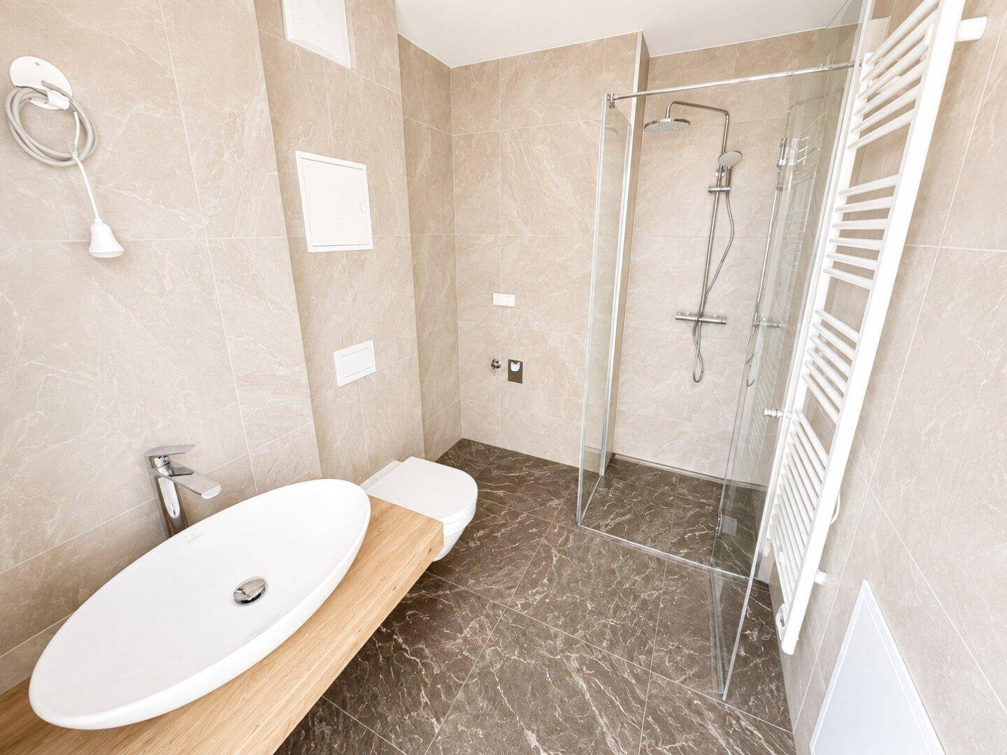 Modernes Badezimmer mit begehbarer Dusche, eleganten Fliesen und beheiztem Handtuchhalter.