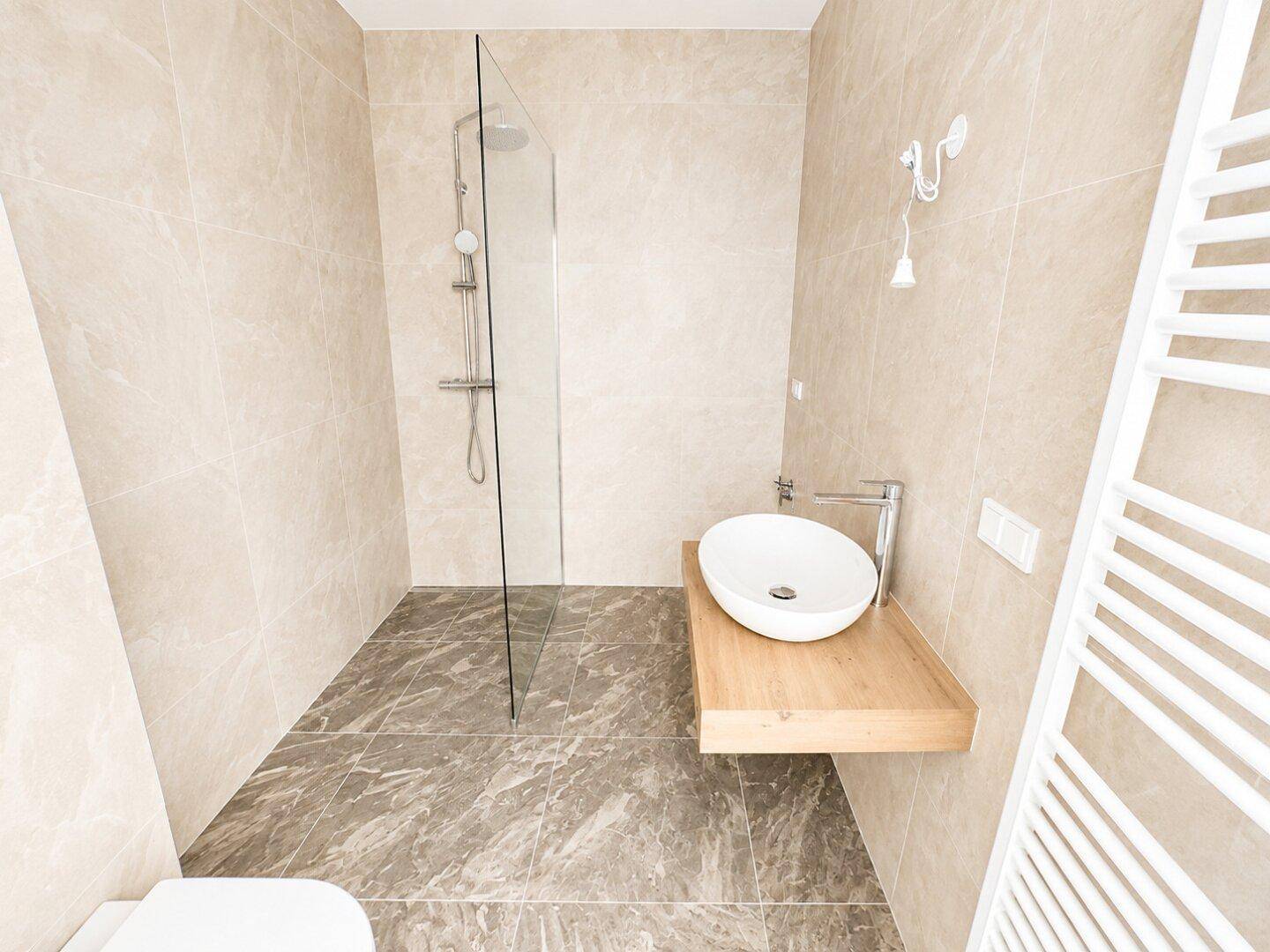 Modernes Badezimmer mit begehbarer Dusche, beigefarbenen Fliesen und Holzwaschtisch.