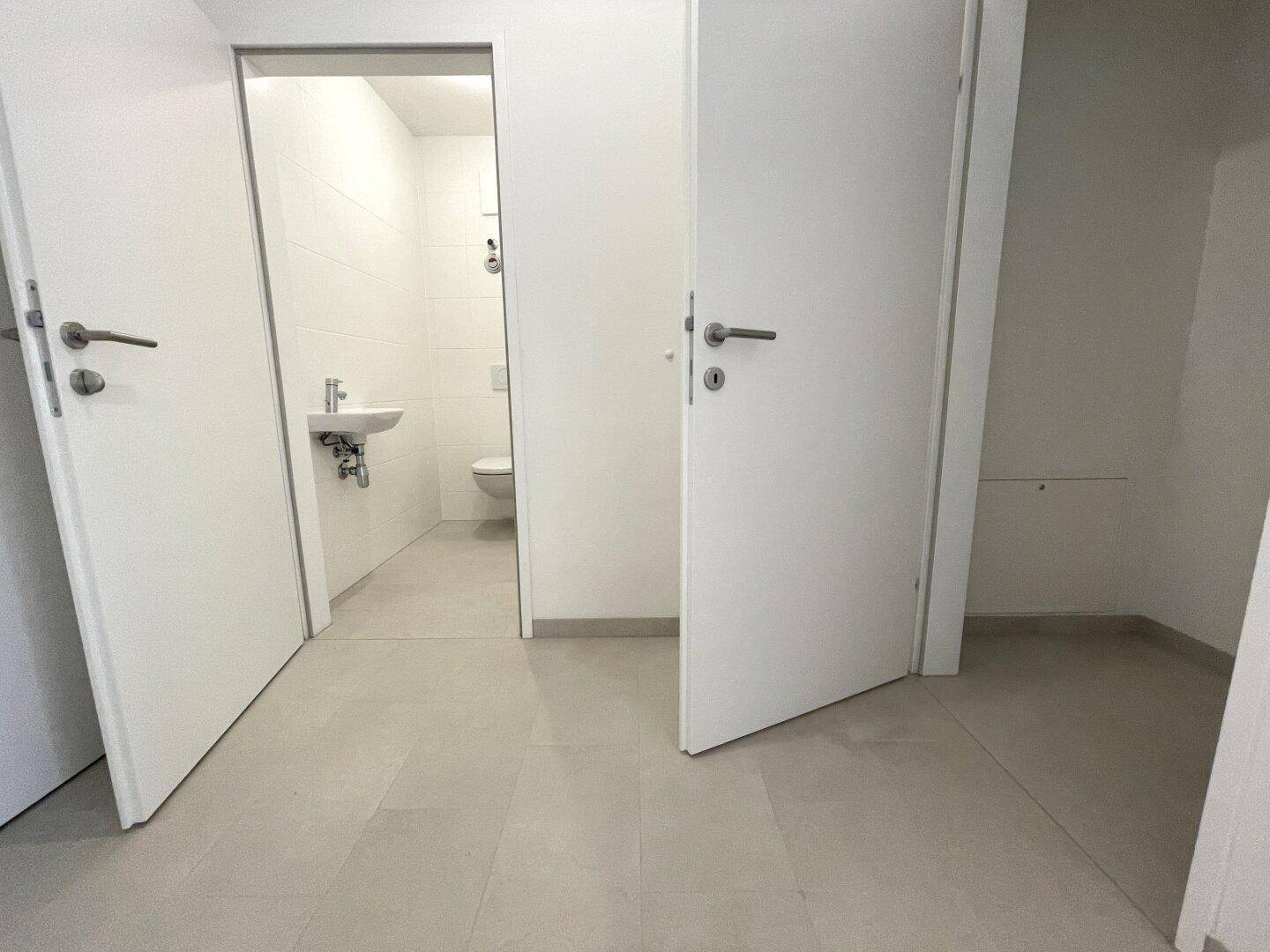 Flur mit Zugang zu einem Gäste-WC, ausgestattet mit hellem Fliesenboden.