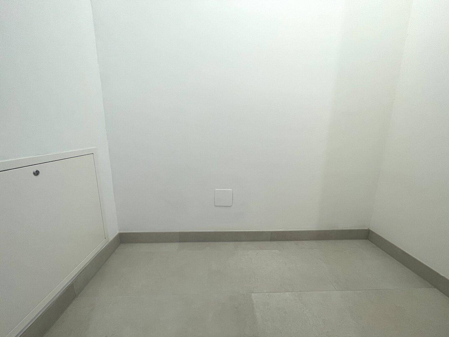 Kleiner Abstellraum mit hellem Fliesenboden und weißen Wänden, ideal für Lagerzwecke.