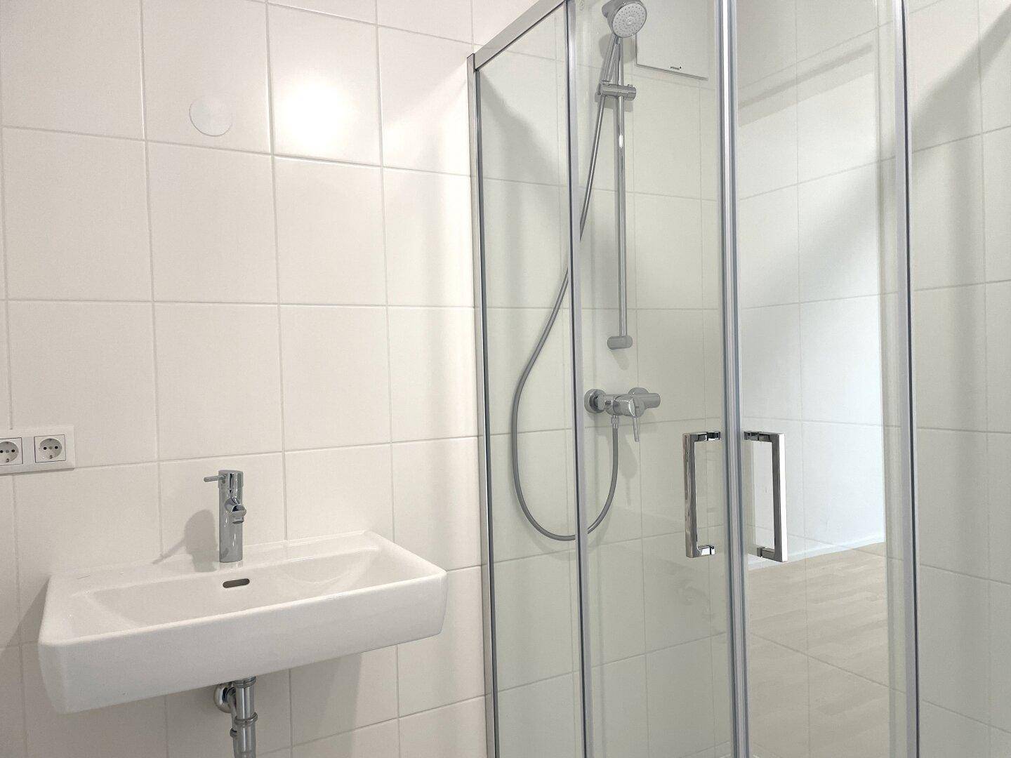 Helles Badezimmer mit modernem Waschbecken und Duschkabine mit Glasabtrennung.