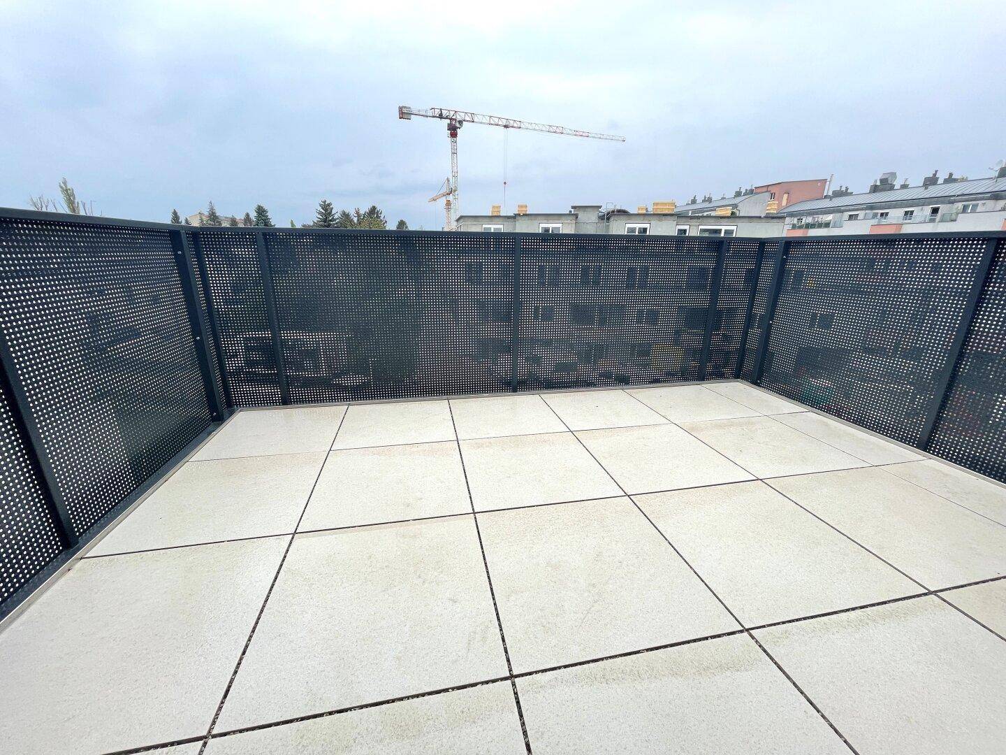 Geräumige Terrasse mit Fliesenboden und moderner Brüstung, bietet Platz für Entspannung im Freien.