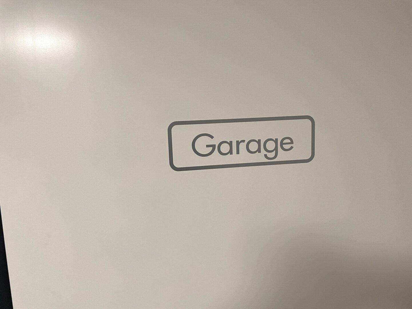 Eine weiße Wand mit der Aufschrift "Garage", die auf einen Parkbereich hinweist.