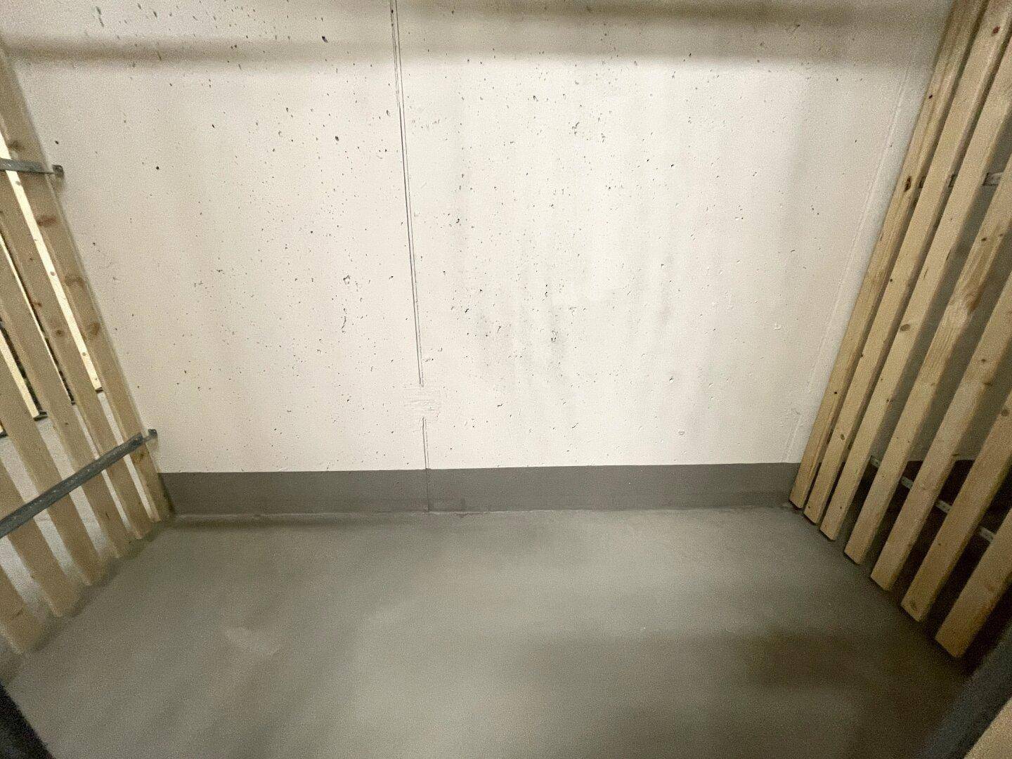 Ein leerer Abstellraum mit Holzwänden und einem einfachen Betonboden.