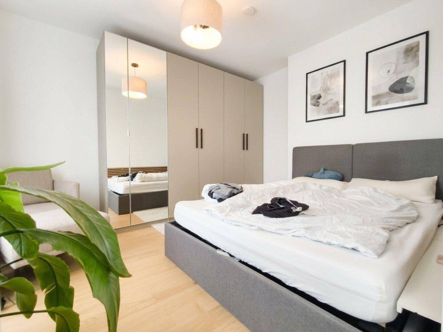 Helles Schlafzimmer mit großem Doppelbett, integrierten Spiegelschränken und Holzboden.