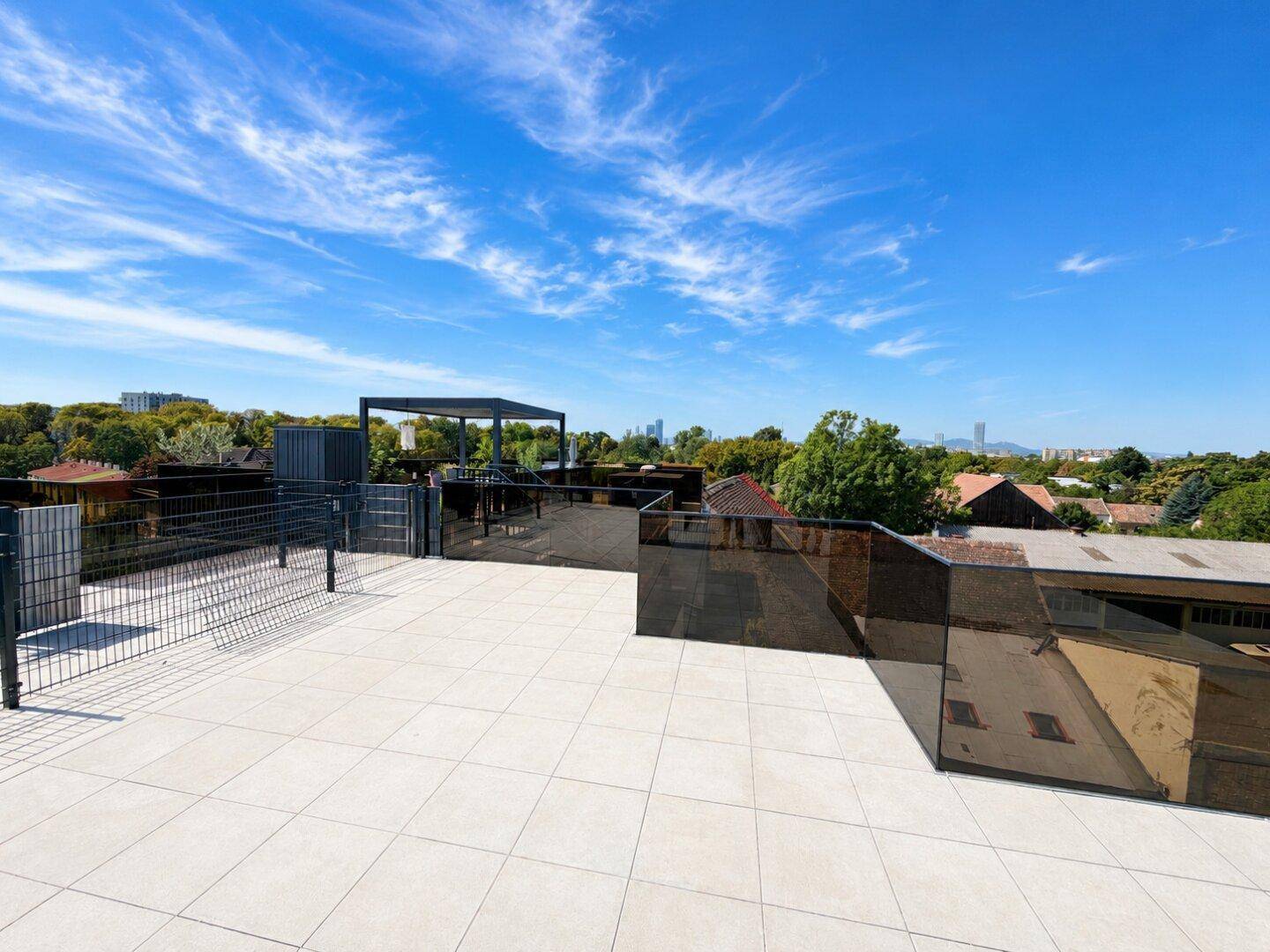 Weitläufige Dachterrasse mit moderner Gestaltung, Fliesenboden und Panoramablick auf die Umgebung und die Stadt.