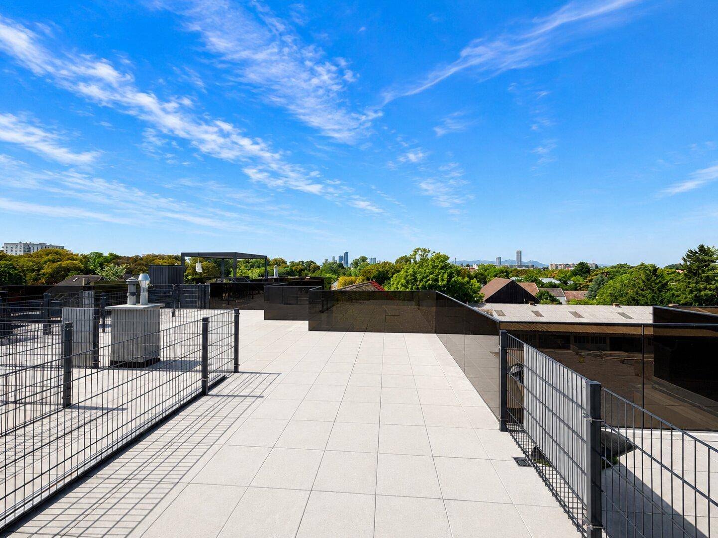 Weitläufige Dachterrasse mit hellen Fliesen und Panoramablick auf die Umgebung und die Stadt.