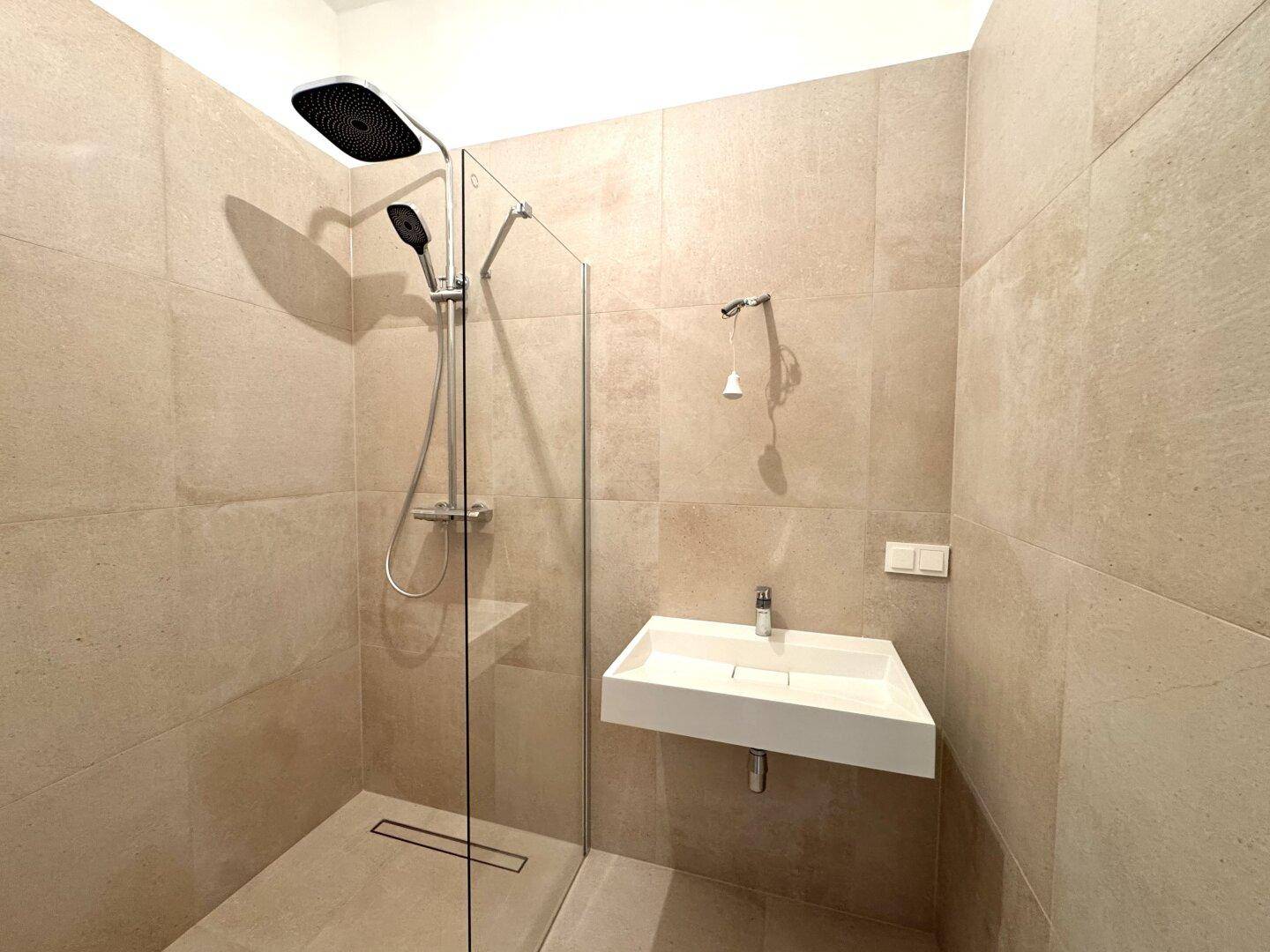 Modernes Badezimmer mit begehbarer Dusche, Regenduschkopf und eleganten beigefarbenen Fliesen.