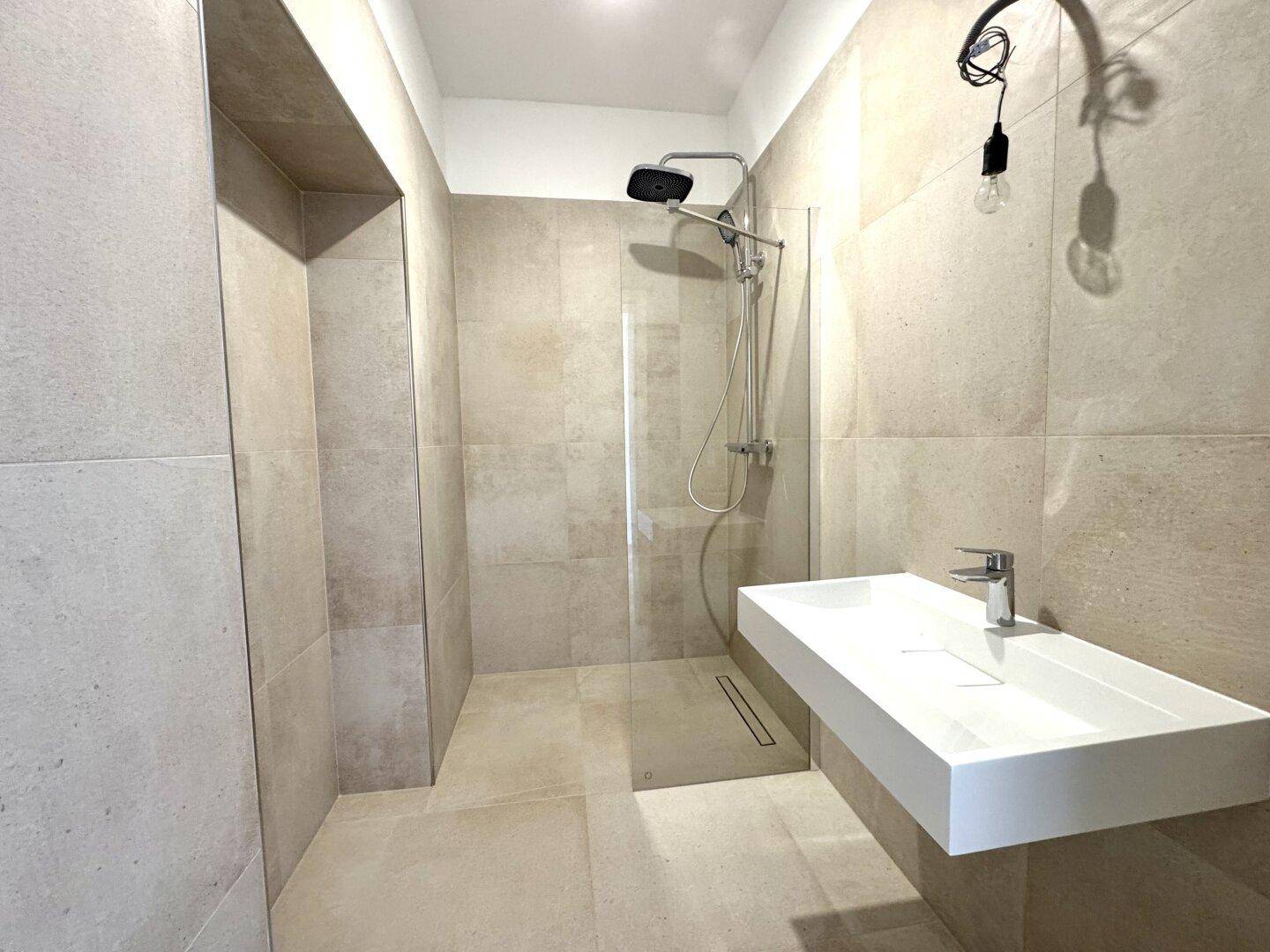 Modernes Badezimmer mit begehbarer Dusche, großformatigen Fliesen und elegantem Waschtisch.