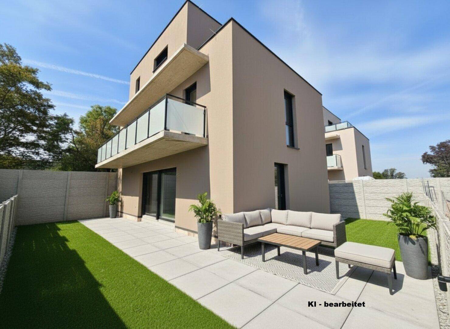 Moderne Terrasse mit Sitzgruppe und Kunstrasen im Gartenbereich eines Neubaus.