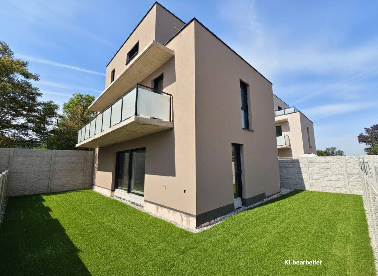 Moderner Neubau mit Garten und Betonzaun unter blauem Himmel.