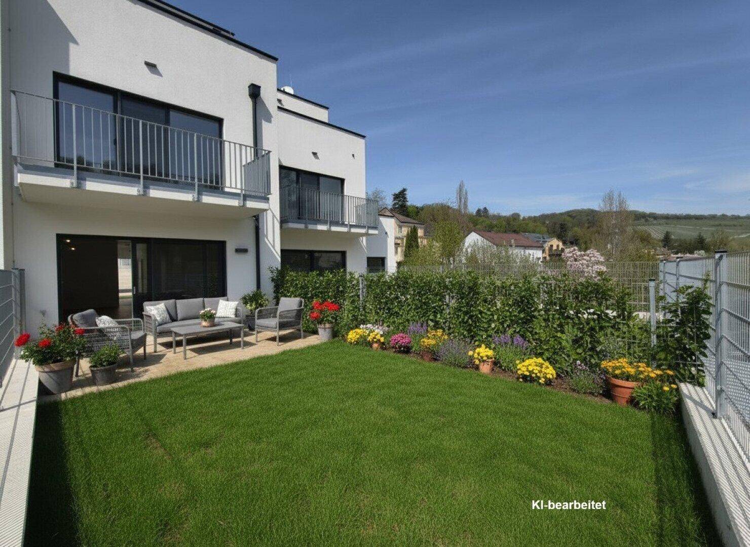 Gepflegter Gartenbereich mit Rasenfläche, Terrasse und Blumenbeeten vor dem Neubau.
