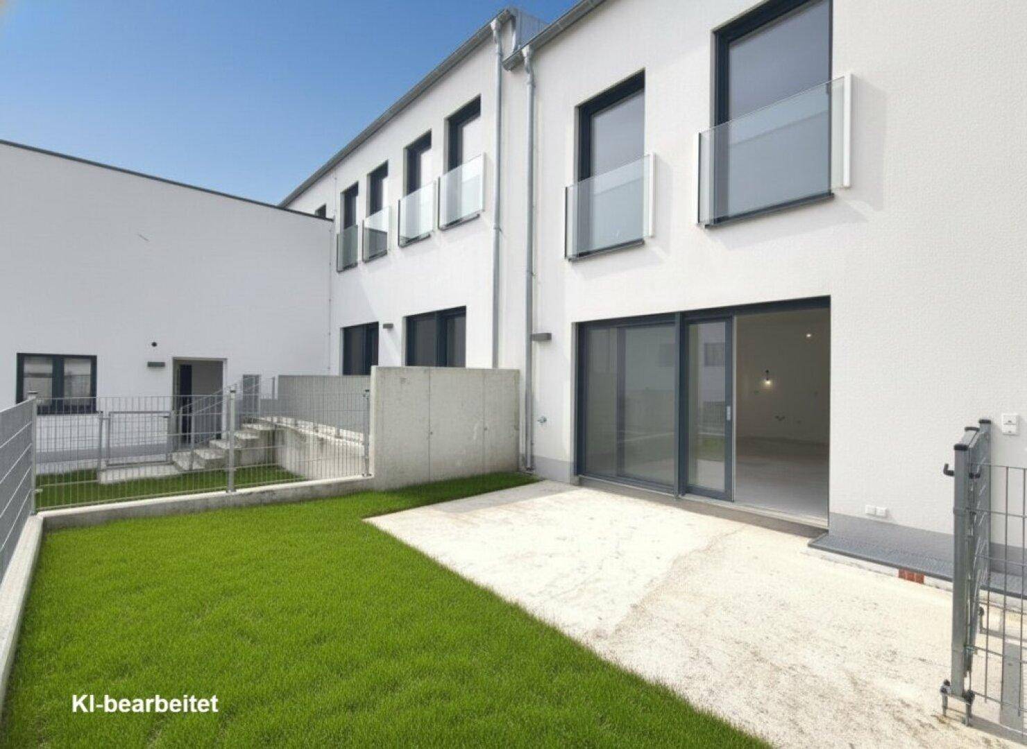 Unmöblierte Terrasse mit Rasenfläche und Zugang zum modernen Neubau.