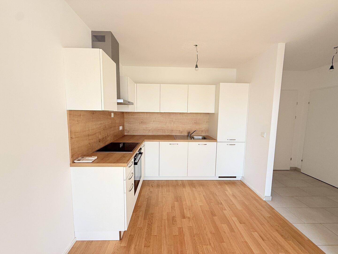 Moderne Einbauküche mit weißen Schränken, Holz-Arbeitsplatte und integrierten Geräten.