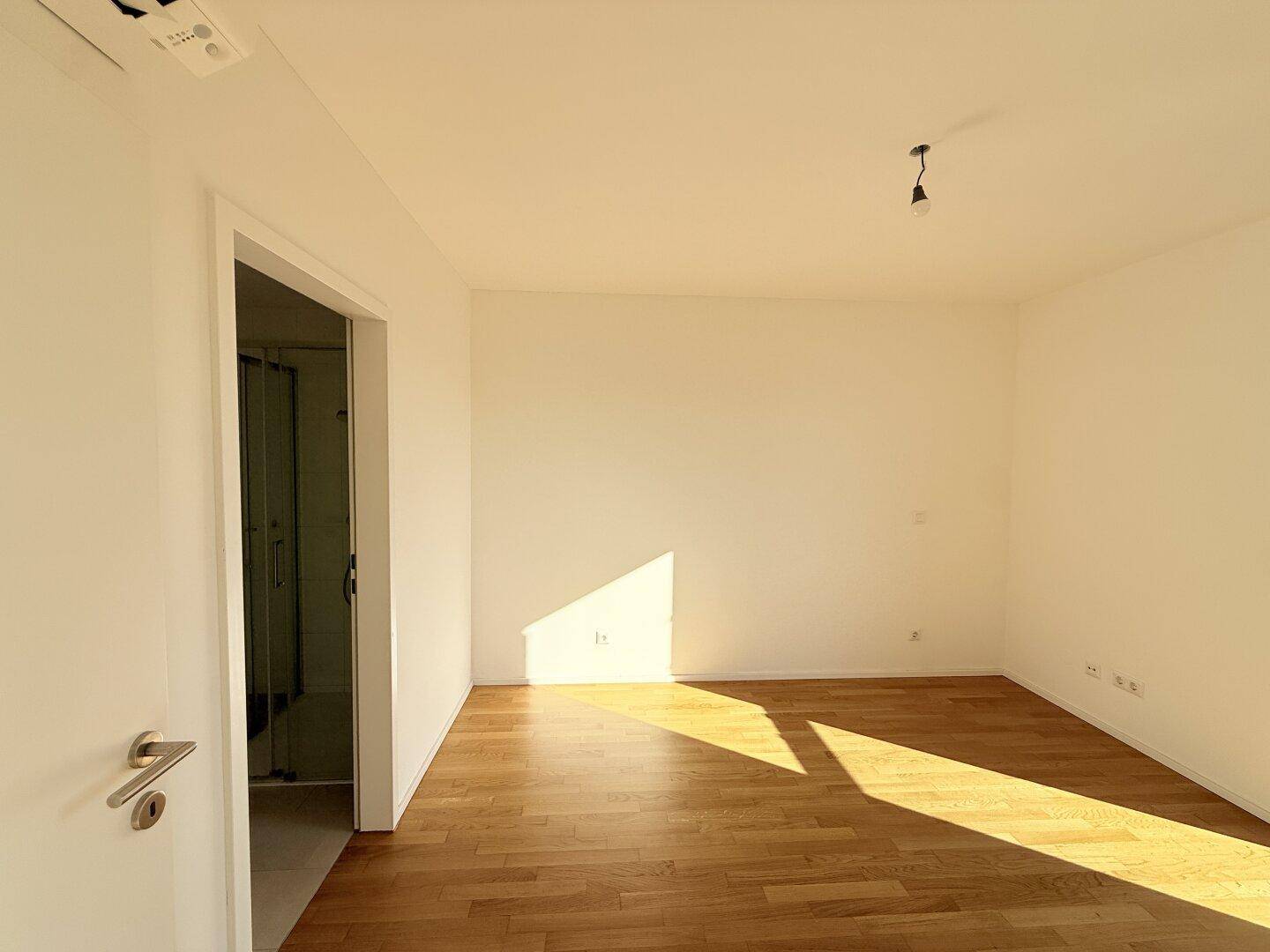 Helles Schlafzimmer mit Holzboden und direktem Zugang zu einem modernen Badezimmer.