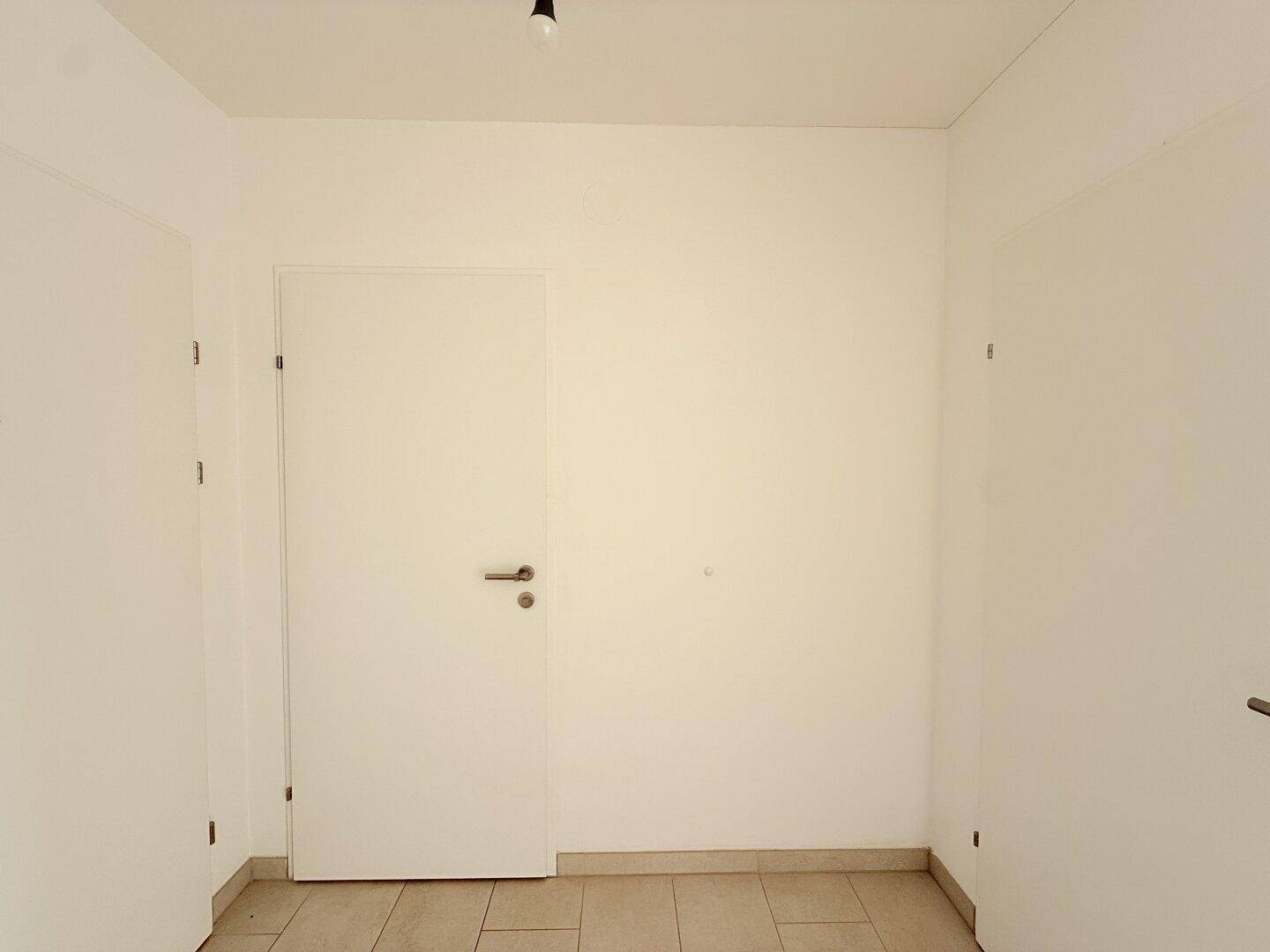 Heller Flur mit Fliesenboden und zwei Türen, bietet einen sauberen Eingangsbereich.
