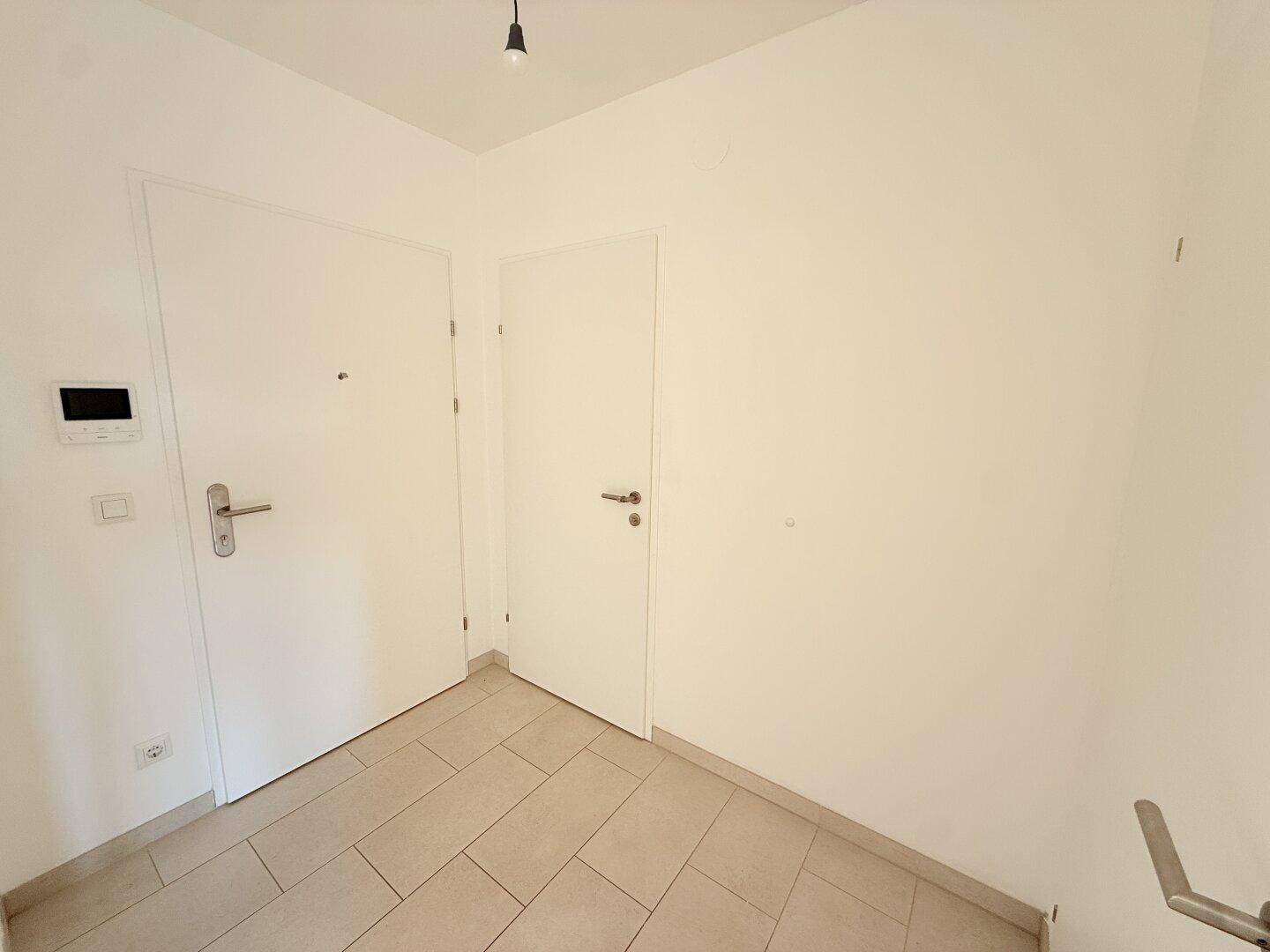 Eingangsbereich mit Fliesenboden, Gegensprechanlage und zwei Türen.