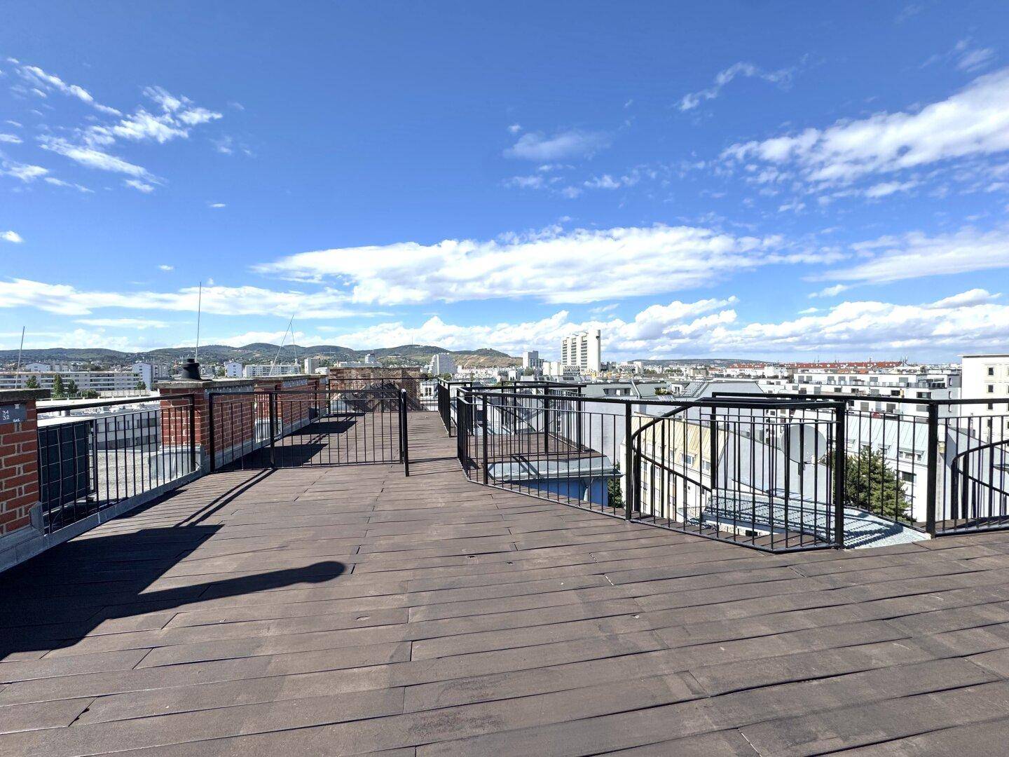 Weitläufige Dachterrasse mit Holzboden und Panoramablick über die Stadt und die Umgebung.