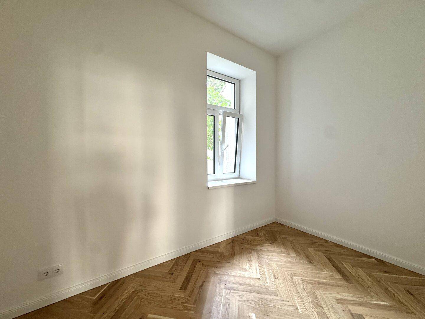 Kleines, helles Zimmer mit Fischgrätparkett und einem Fenster, perfekt für Gäste oder als Büro.