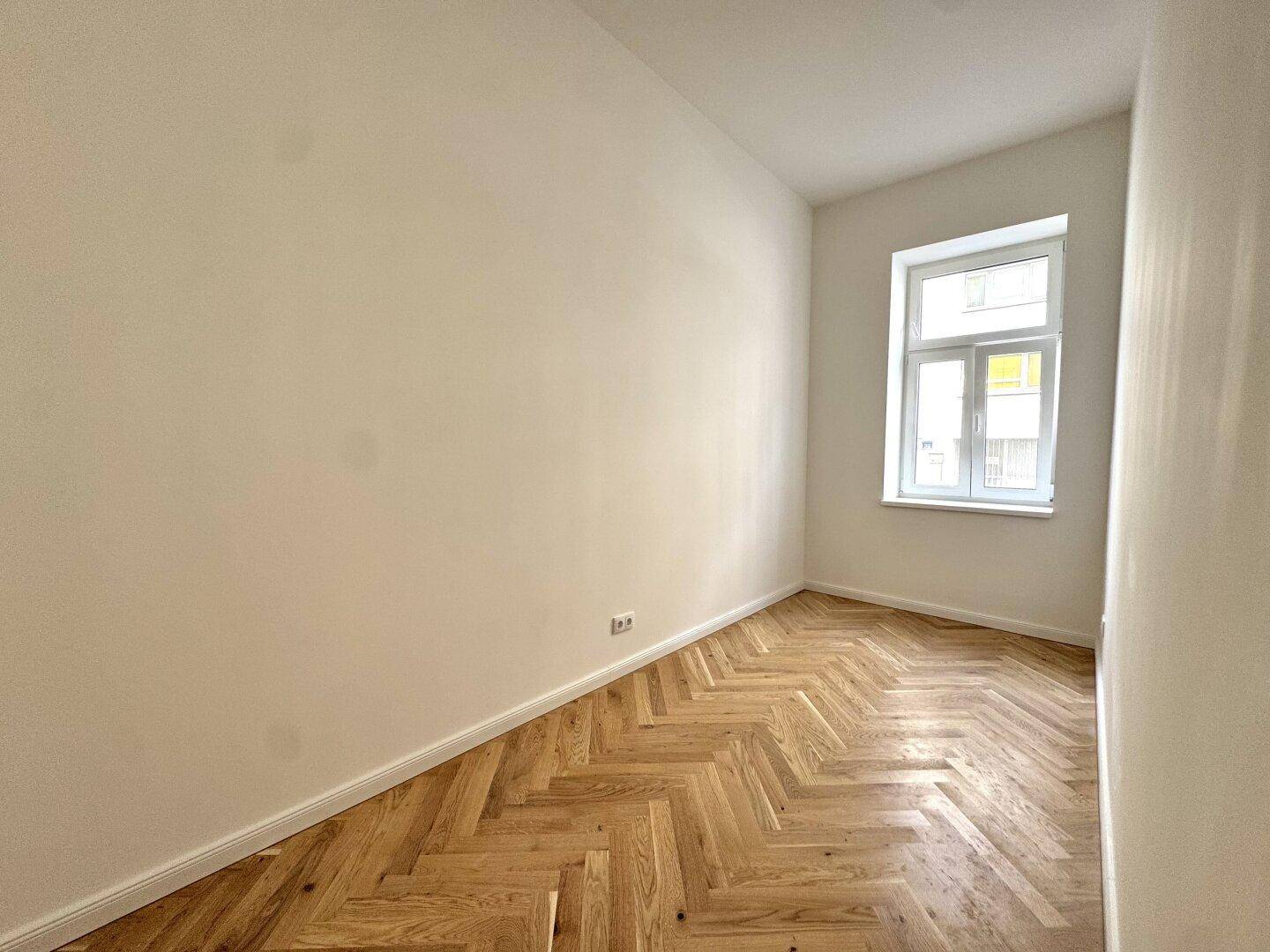 Gemütliches Zimmer mit Fischgrätparkett und einem Fenster, ideal als Kinder- oder Arbeitszimmer.