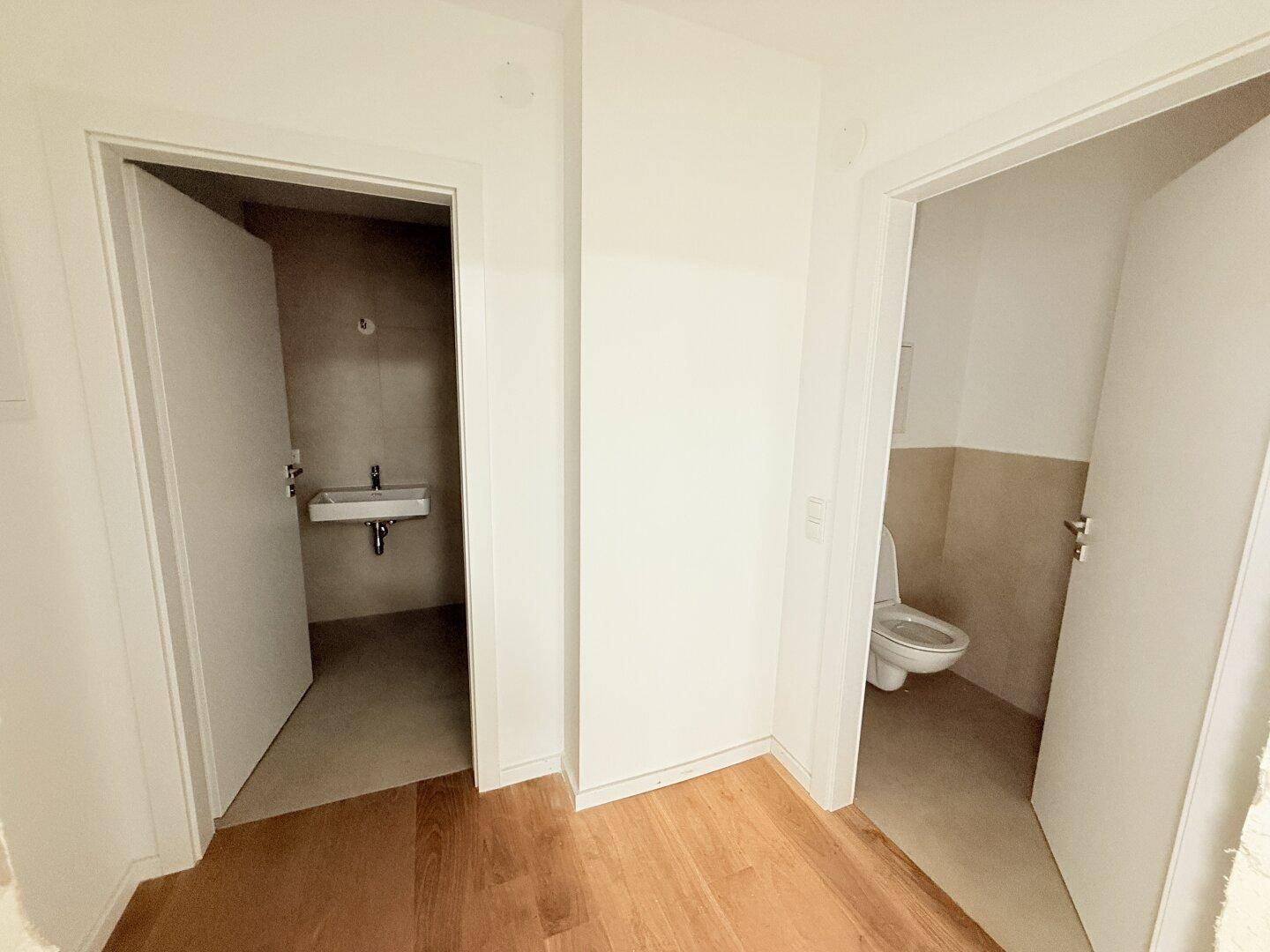 Flur mit Holzboden und Zugang zu zwei separaten Badezimmern oder Toiletten.