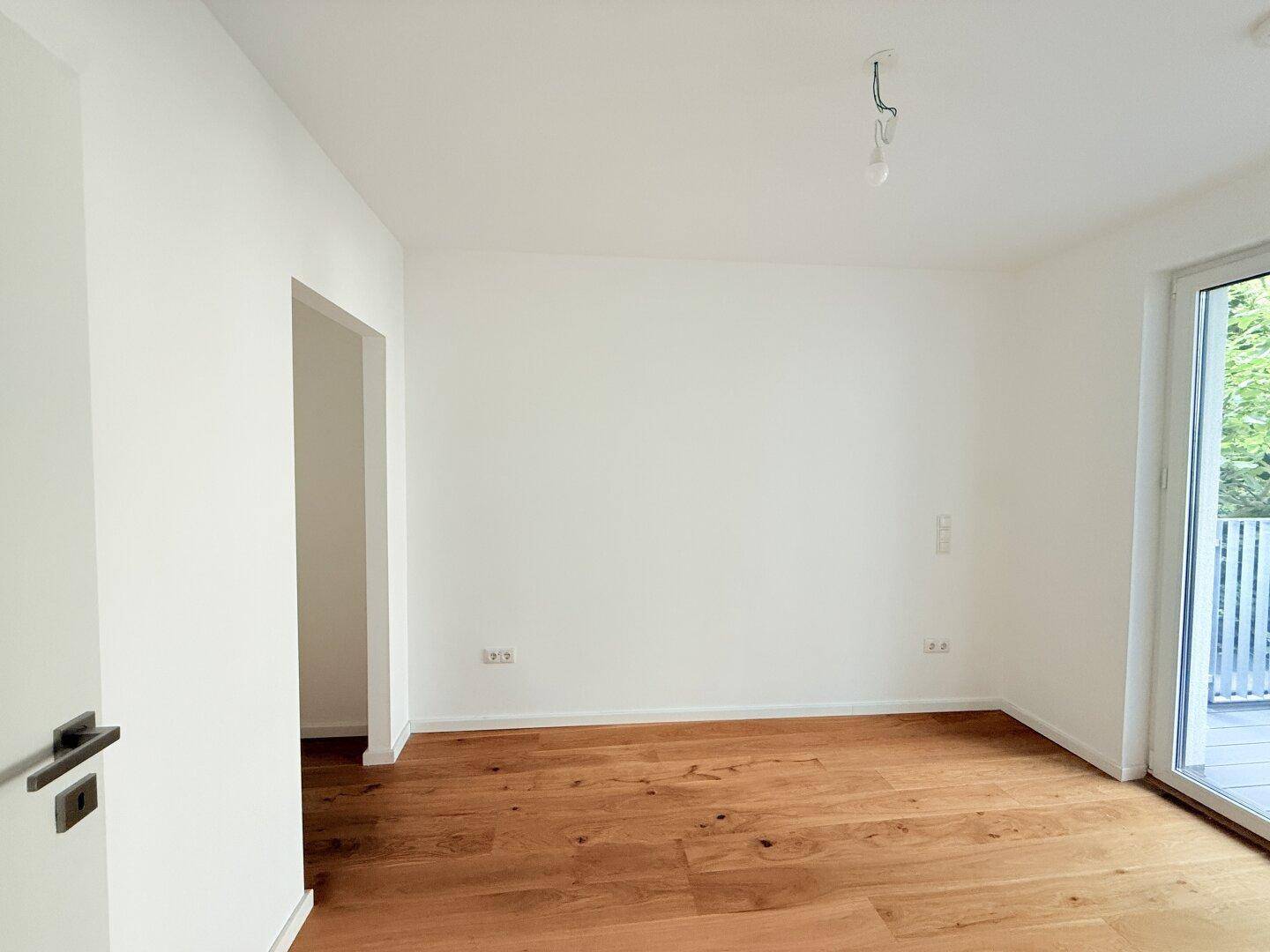 Geräumiges Schlafzimmer mit Holzboden und Zugang zu einem weiteren Raum.