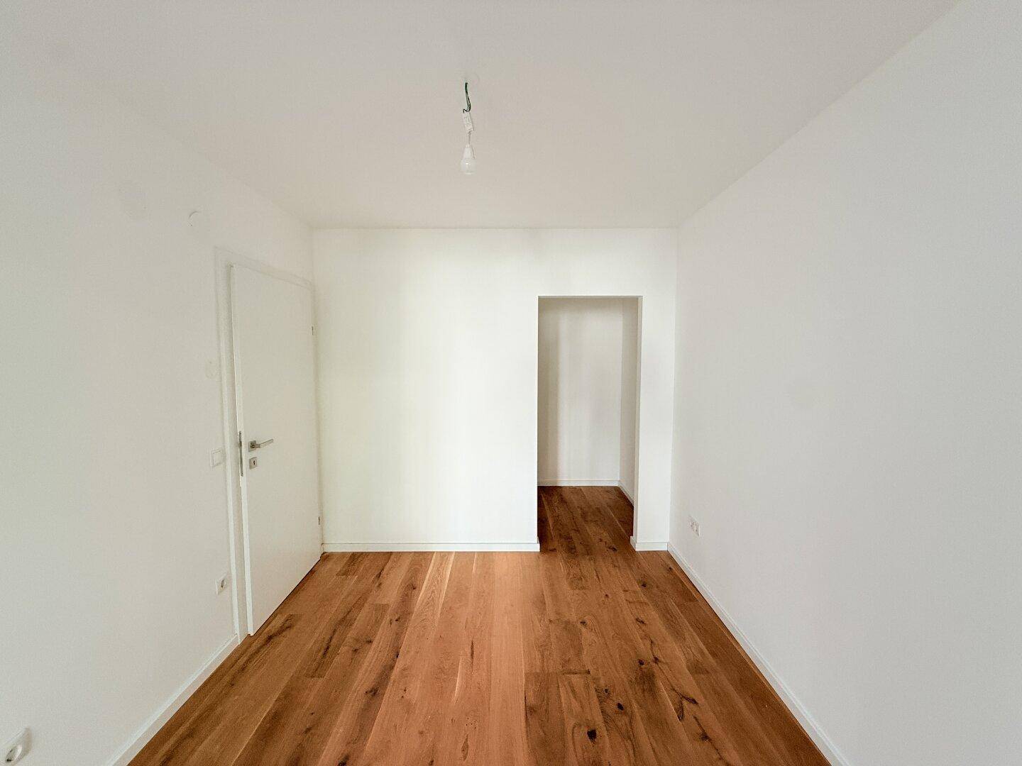 Schlafzimmer mit Holzboden und Zugang zu einem angrenzenden Raum.