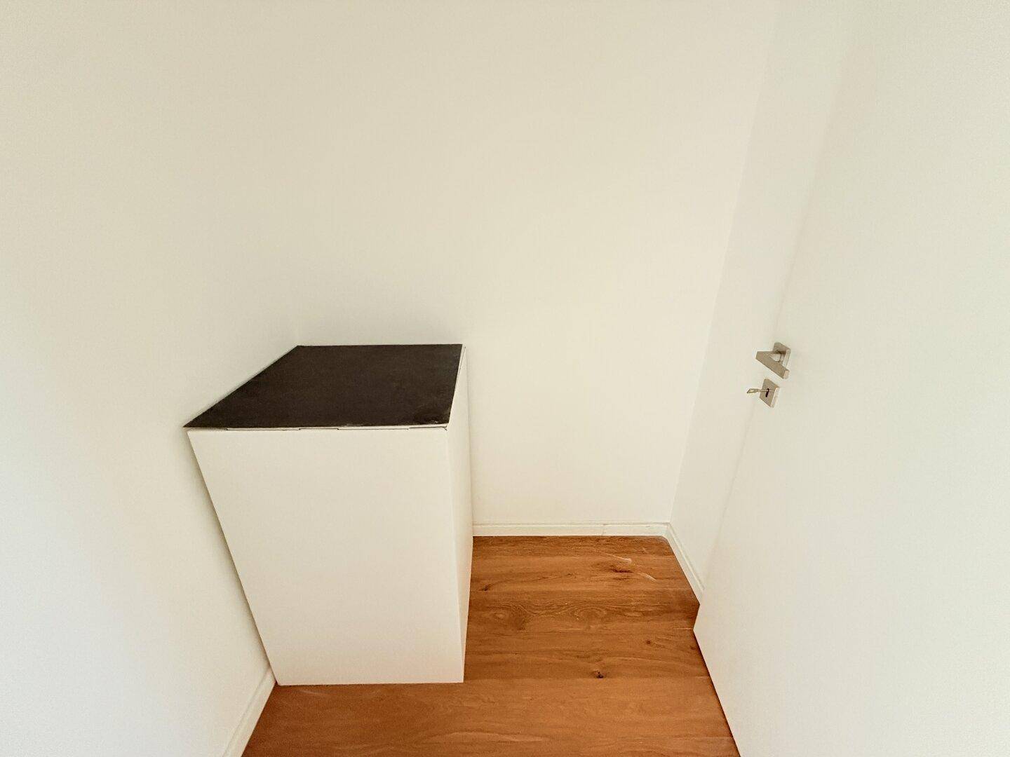 Kleiner Abstellraum mit Holzboden und einer Ablagefläche.