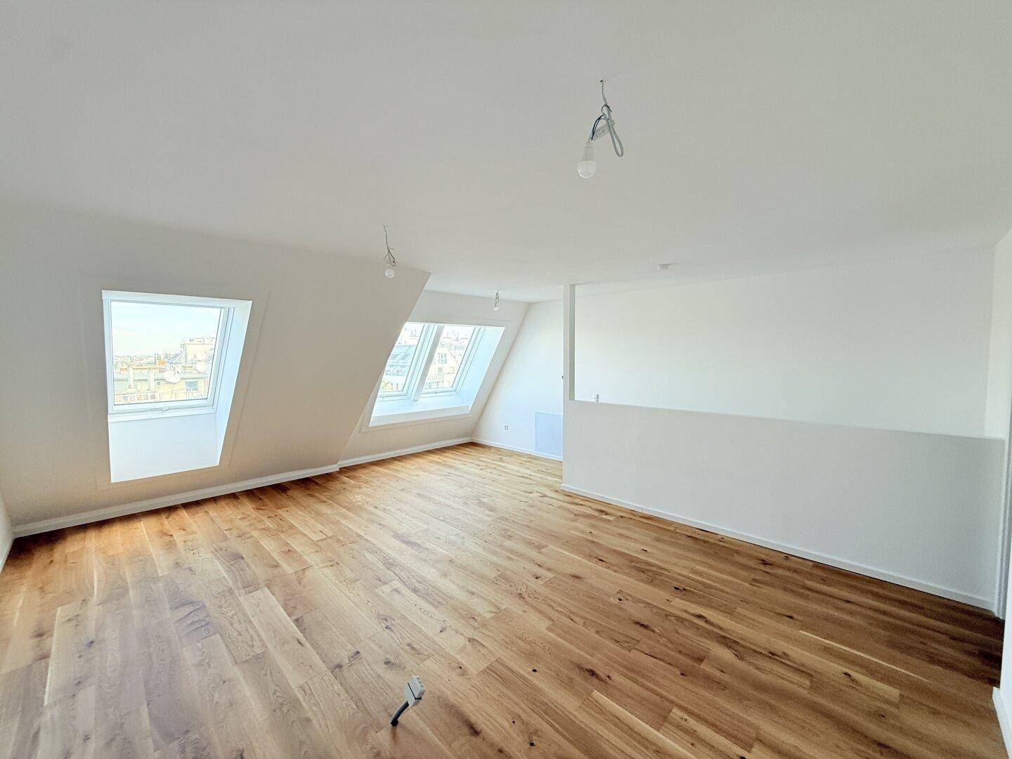 Lichtdurchflutetes Dachgeschosszimmer mit mehreren Dachfenstern und neuem Holzboden.