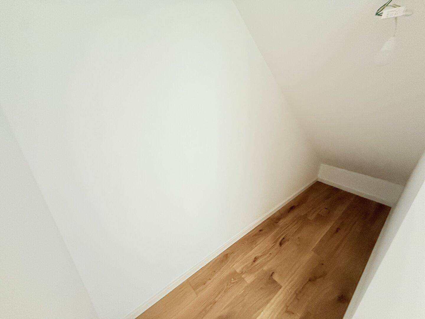 Praktischer Abstellraum im Dachgeschoss mit Holzboden und schrägen Wänden.
