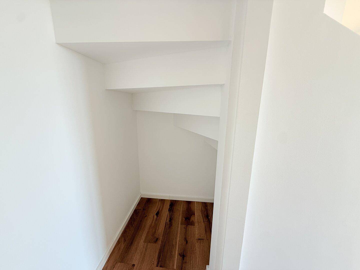 Praktischer Stauraum unter der Treppe mit Holzboden, ideal für zusätzlichen Lagerplatz.
