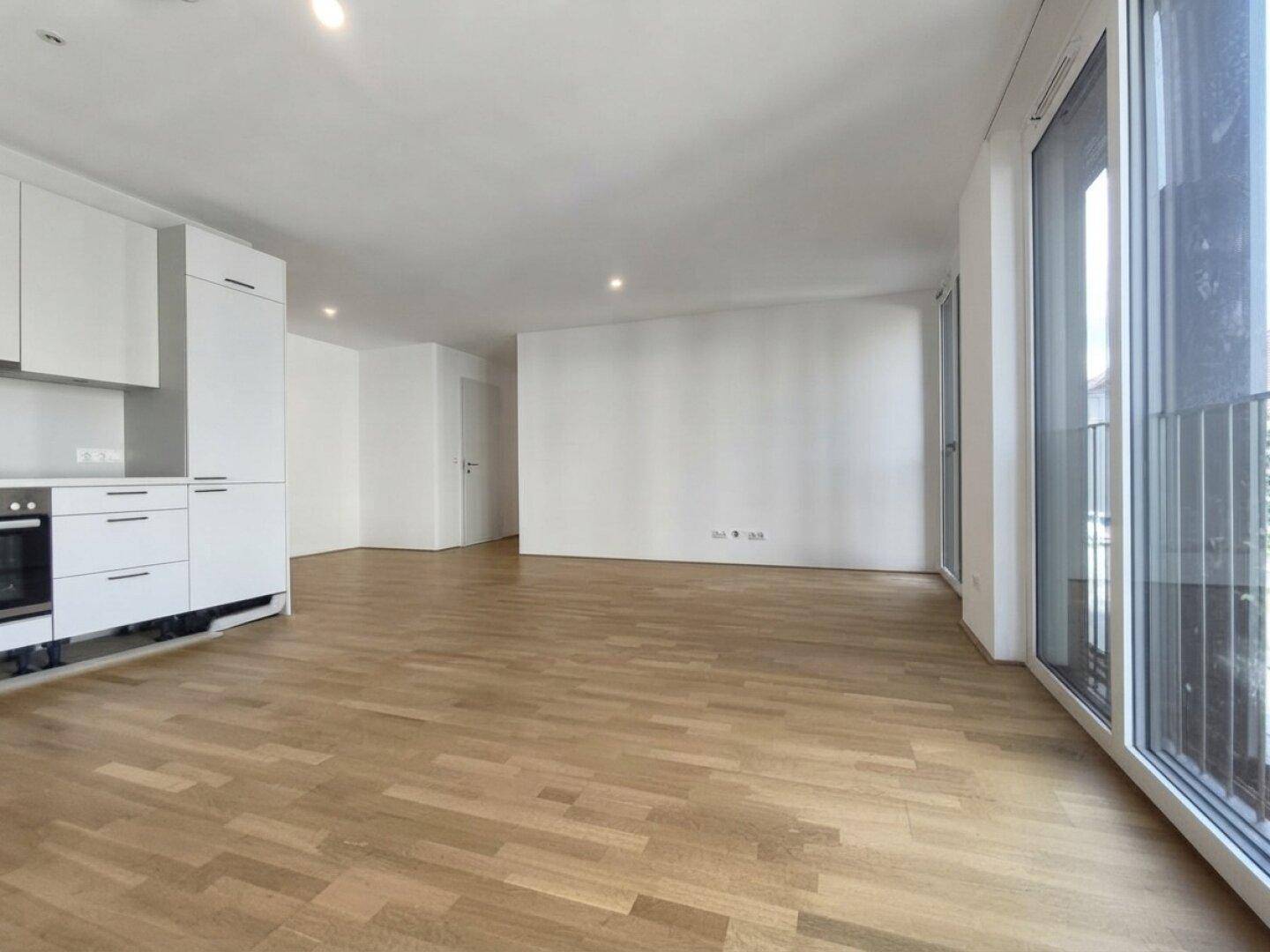 Moderner Wohn- und Essbereich mit integrierter Küchenzeile und großen Fenstern für viel Licht.