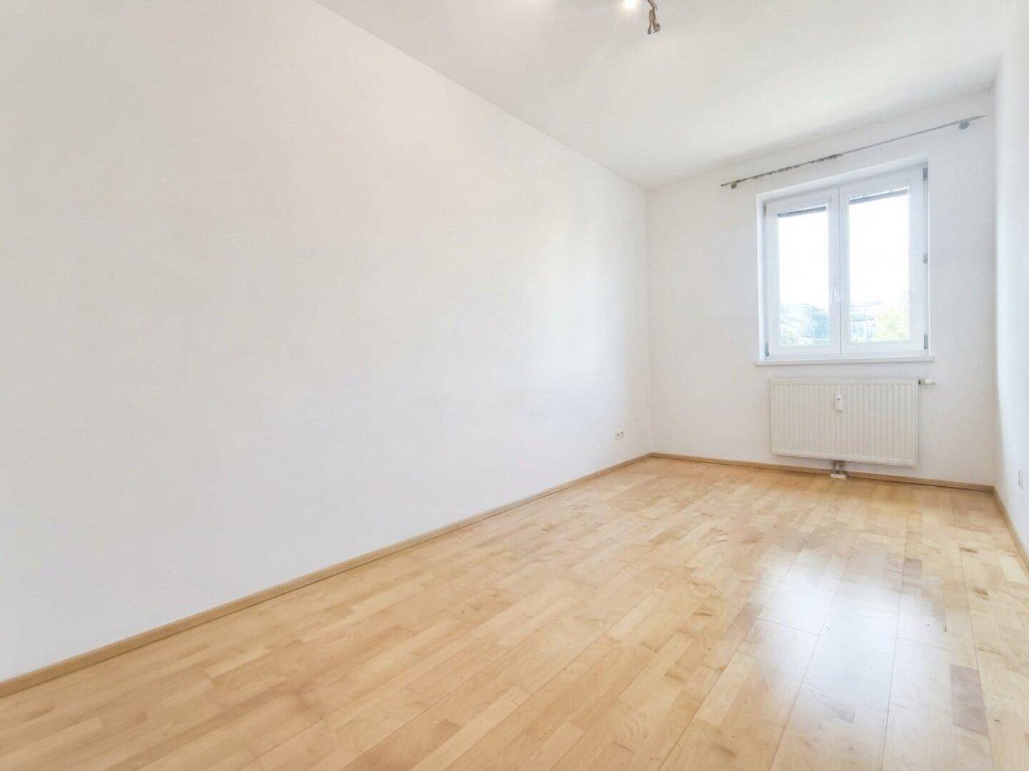 Geräumiges Zimmer mit Holzboden und viel Tageslicht.