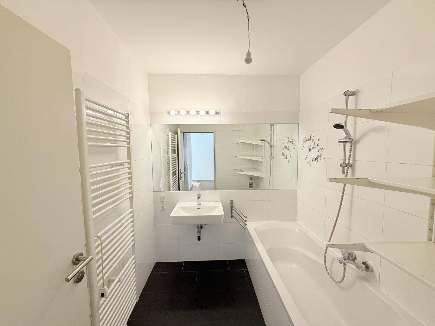 Modernes Badezimmer mit Badewanne, Waschbecken und beheiztem Handtuchhalter.