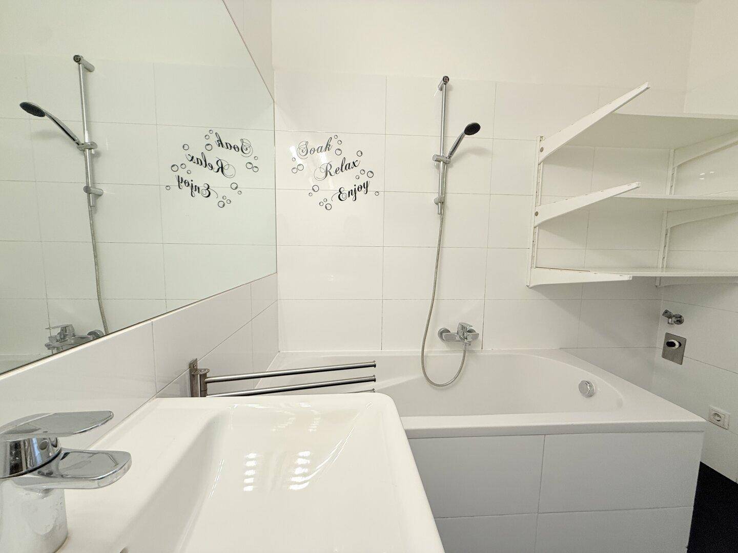 Helles Badezimmer mit Badewanne, Waschbecken und großem Spiegel.