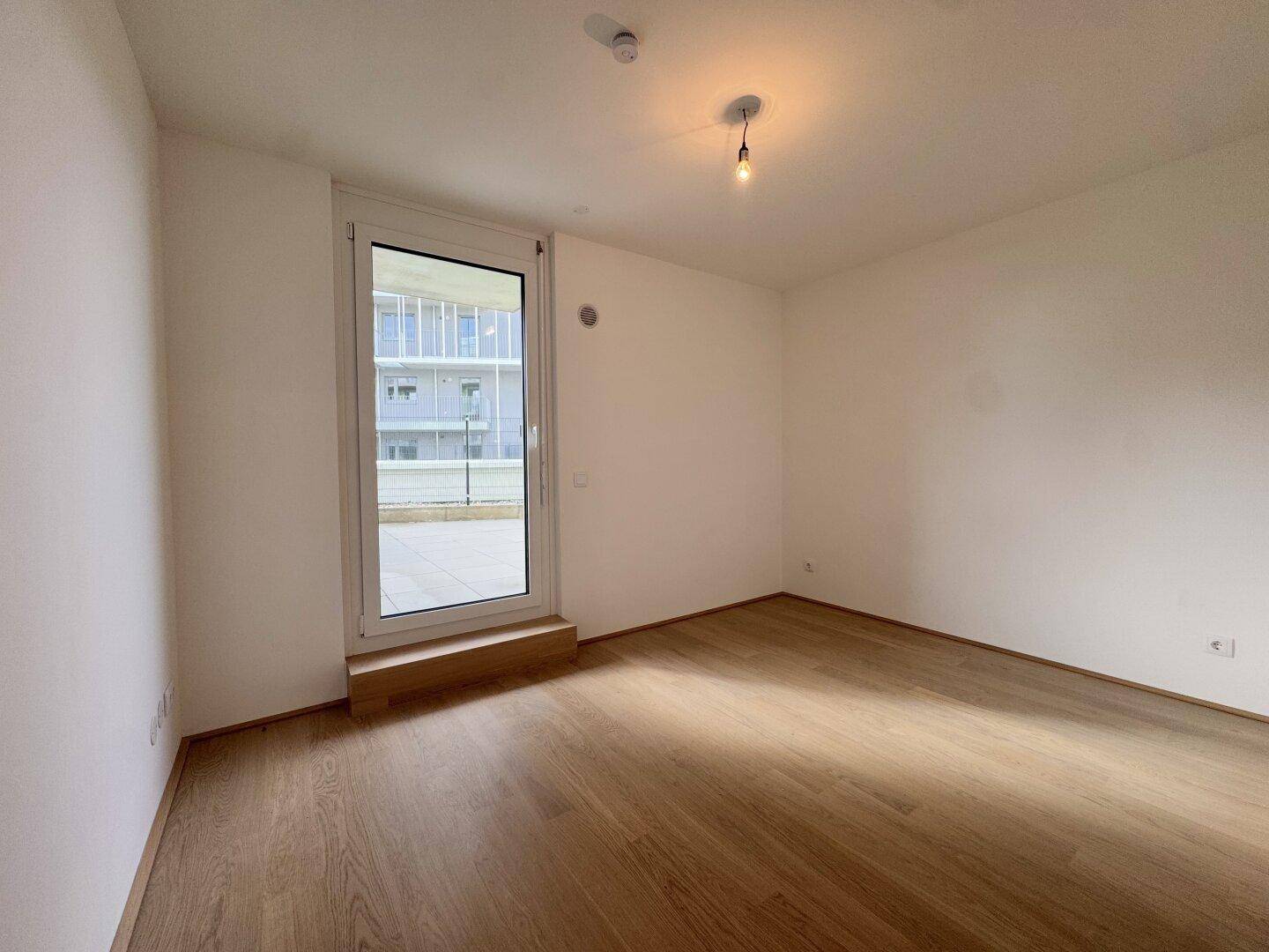 Schlafzimmer mit Holzboden und direktem Zugang zu einer Terrasse oder einem Balkon.