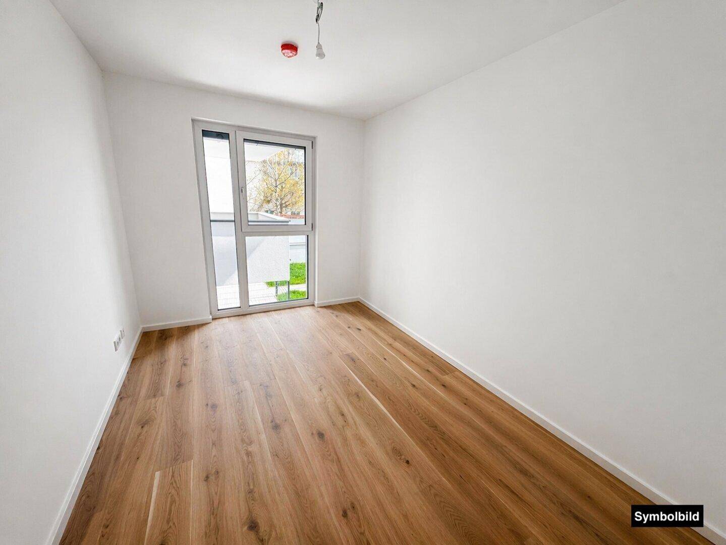 Helles Zimmer mit Eichenparkettboden und großen Fenstern, ideal als Schlaf- oder Arbeitszimmer.